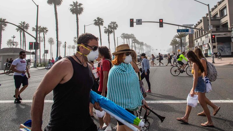 People cross the street, some wearing masks, at Huntington Beach on Saturday. Photograph: Apu Gomes/AFP via Getty Images