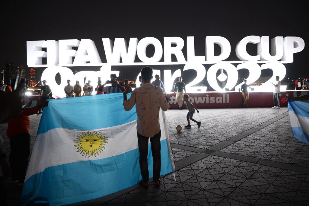 Fans hold an argentinian flag in front of a Fifa World Cup sign in Doha on Tuesday, November 15th ahead of the Qatar World Cup. Photograph: Anne-Christine Poujoulat/AFP/Getty