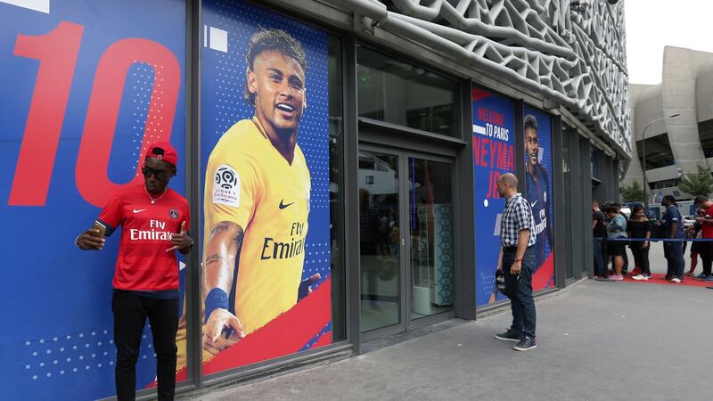 A PSG fan poses for a picture next to a poster of Neymar outside the club megastore. Photo: Jonathan Brady/PA