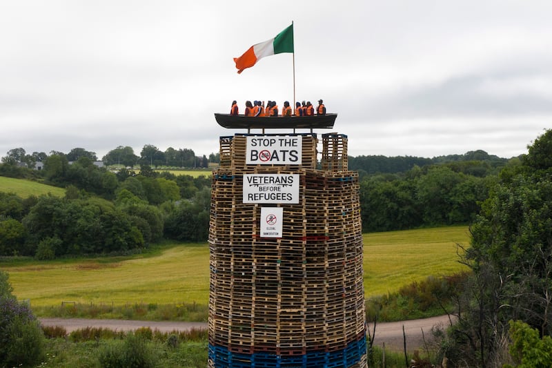 A model of a small boat with several figures depicting migrants inside can be seen on top of a loyalist bonfire on Thursday in Moygashel, United Kingdom. Photograph Charles McQuillan/ Getty Images