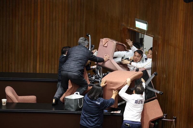 Lawmakers from the main opposition Kuomintang (KMT) (in white) try to break into Parliament where Democratic Progressive Party (DPP) occupied the night to avoid the passing of the third reading of amendments to the Civil Servants Election and Recall Act and other controversial bills at the Legislative Yuan in Taipei. Photograph: I-Hwa Cheng/AFP