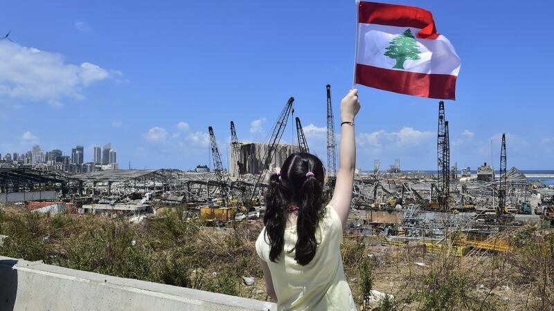Young woman waves a  Lebanese flag at the site of the deadly explosion at the port of Beiruit. Photograph:  Houssam Shbaro/Anadolu Agency via Getty