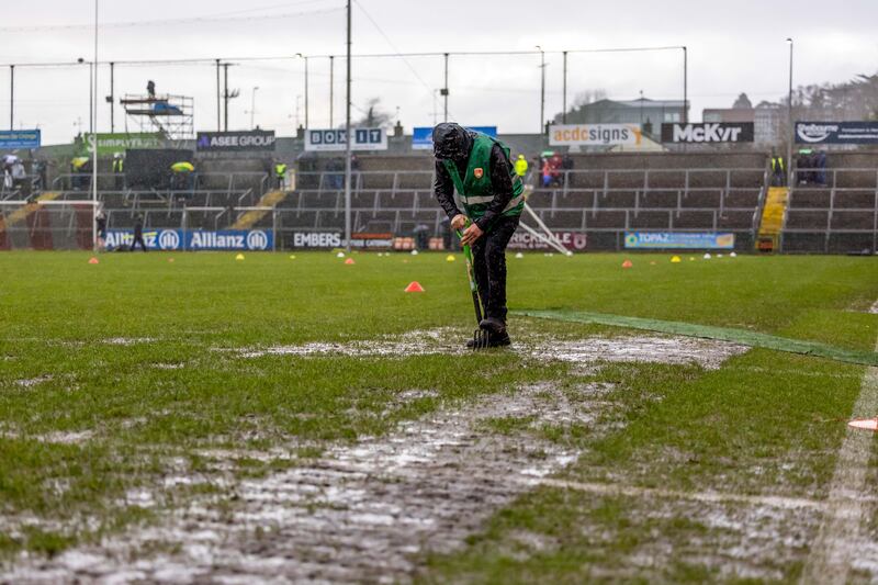 Groundsmen work on clearing water from the pitch at the Athletic Grounds as heavy rain falls before the Division 1 game between Armagh and Donegal on Sunday. Photograph: Morgan Treacy/Inpho