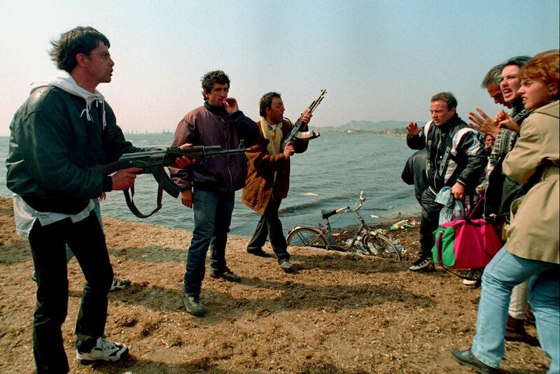 Albanian gunmen demand payment from civilians hoping to board a ship for Italy near the port of Durres, Albania in March 1997. Photograph: Reuters