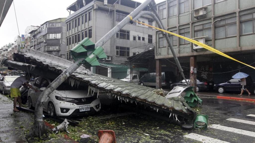 A man looks at a car damaged by fallen roof near a bent traffic light caused by strong winds from Typhoon Soudelor in Taipei, Taiwan. Photograph: Pichi Chuang/Reuters