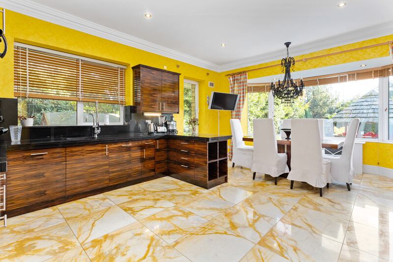 Kitchen with eating area overlooking garden, custom-built units topped with black marble worktops