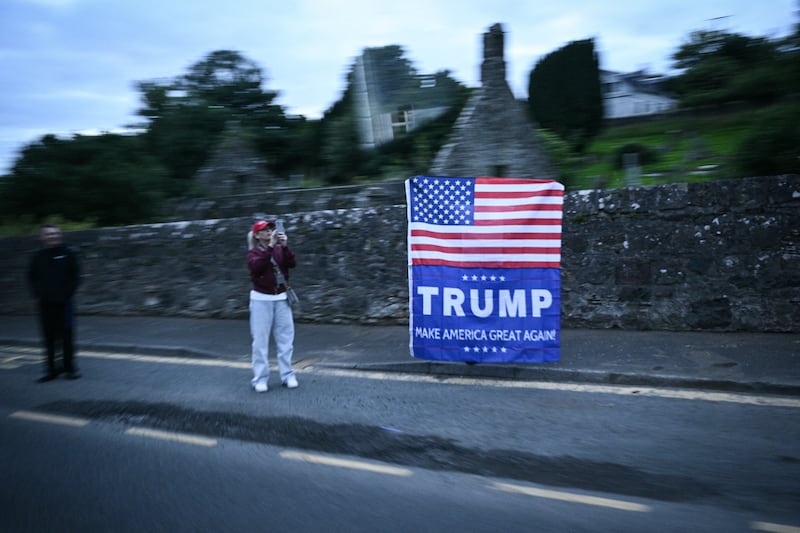 People cheer with a US national flag reading "Trump, Make America Great Again" as the US president's cars delegation drive past them near Prestwick airport. Photograph: Getty Images