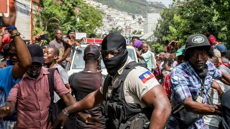 People cheer as a police car drives past at Petionville police station where armed men accused of being involved in the assassination of President Jovenel Moïse are being held in Port au Prince, Haiti. Photograph:  Valerie Baeriswyl/AFP via Getty Images