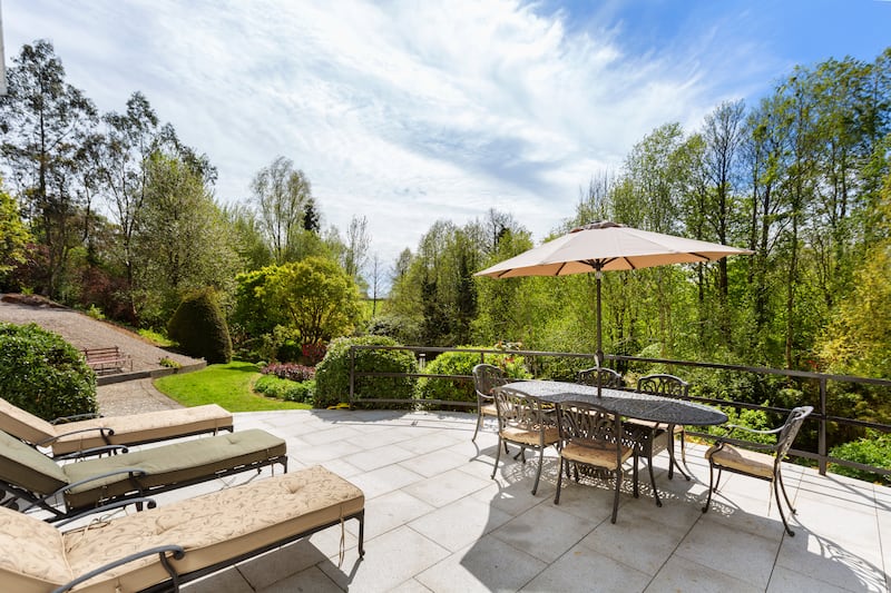 Sunny patio sheltered by a bank of trees