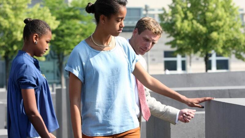Malia Obama  touches one of the stelae at the Memorial to the Murdered Jews of Europe  in Berlin, next to her sister Sasha and Uwe Neumaerker, director of the foundation for the memorial. Photograph: Adam Berry/Getty Images
