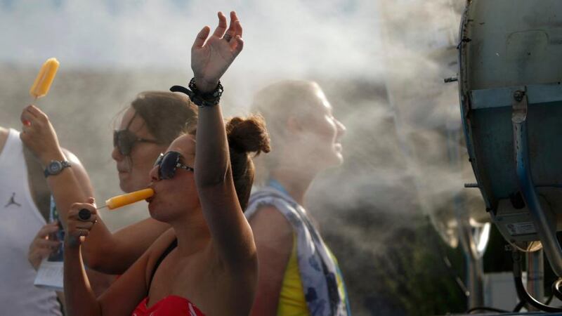 Spectators cool off with ice pops in front of a misting fan at the Australian Open in Melbourne, where temperatures were again over 40 degrees Celsius. Photograph: Jason Reed. Photograph: Reuters