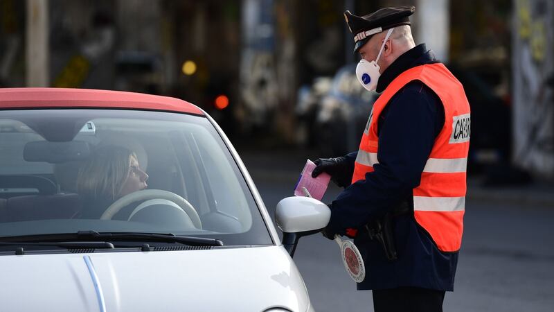 An Italian Carabinieri police officer, wearing a respiratory mask as part of precautionary measures against the spread of the new COVID-19 coronavirus, performs driving permission controls in Milan on March 10, 2020. (Photo by MIGUEL MEDINA/AFP via Getty Images)