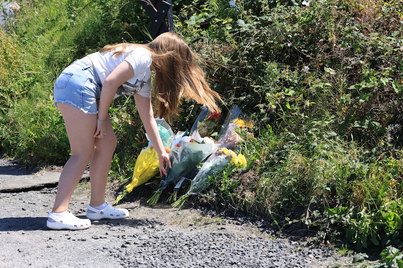 Mick O'Neill's granddaughter, Mya, leaves flowers at the scene at Collinstown lane, Dublin where the award-winning photojournalist was involved in a fatal crash. Photograph: Stephen Collins/Collins Photos