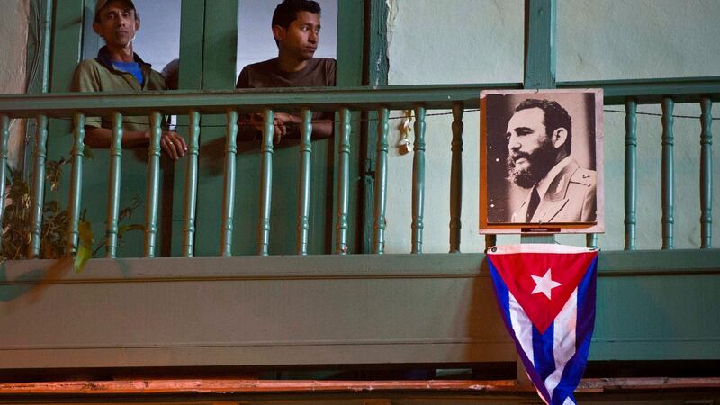 Residents stand  next to an image of the late Cuban leader Fidel Castro and a Cuban Flag in Havana, Cuba over the weekend. Photograph: Ramon Espinosa/AP Photo