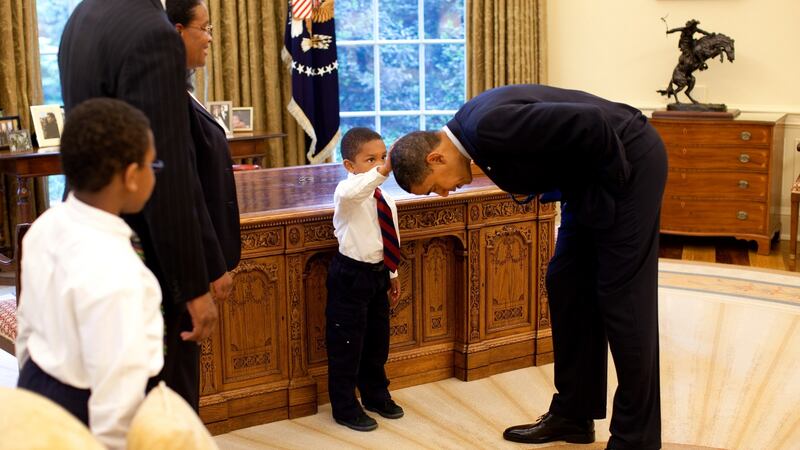 Barack Obama bends over so the son of a White House staff member can pat his head during a visit to the Oval Office on May 8th, 2009. Photograph: Pete Souza/The White House via Getty Images