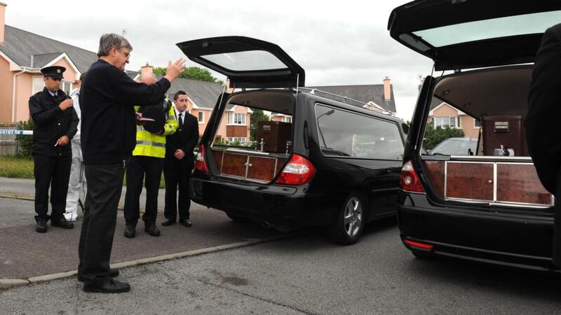Fr Michael Fleming says prayers as the bodies of Jolanta Lubiene and her daughter Erika are removed from their home in Killorglin, Co Kerry, yesterday. Photograph: Eamonn Keogh