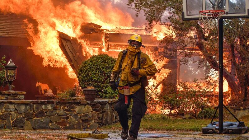 Firefighters work to extinguish a fire at a home as they battle a wildfire in Anaheim Hills. Photograph: Jeff Gritchen/The Orange County Register via AP