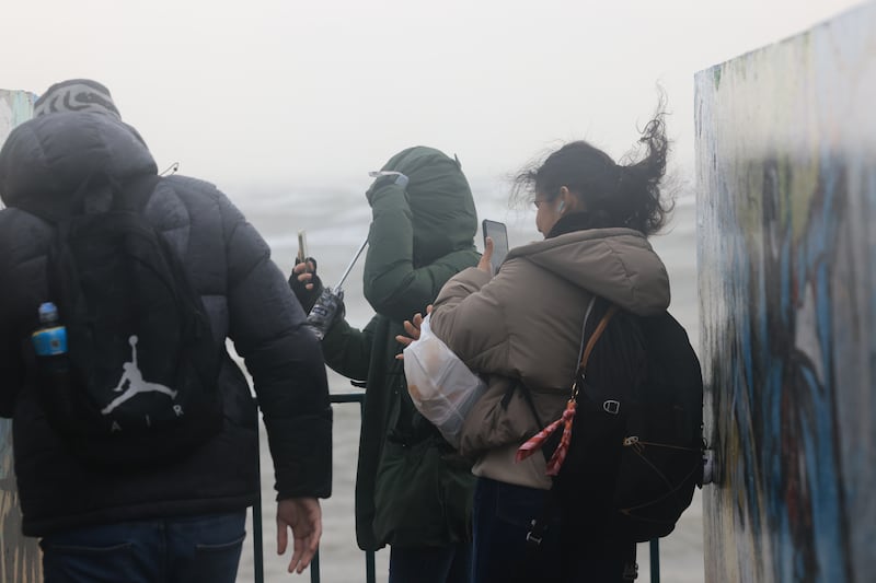 People snap pictures in the wind and rain at Blackrock on Thursday. Photograph: Dara Mac Donaill