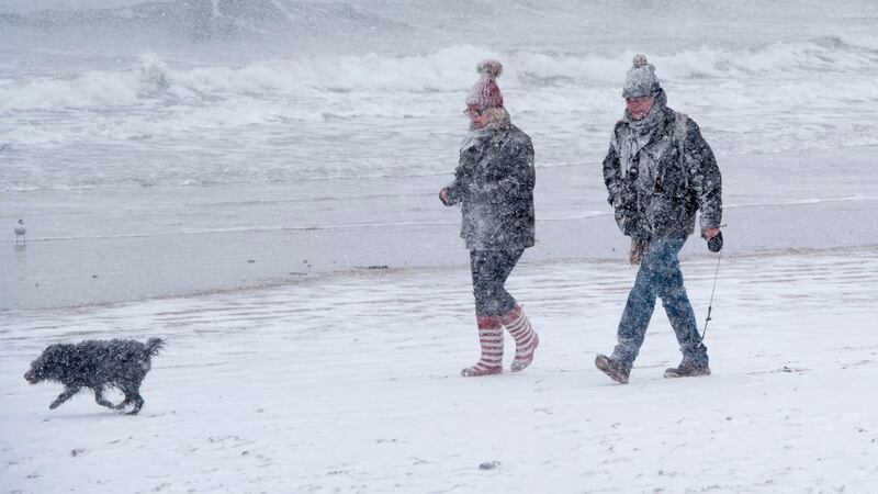 A couple walk their dog on the beach as heavy snow falls in the sea side resort of Scarborough in North Yorkshire on Wednesday. Photograph AFP