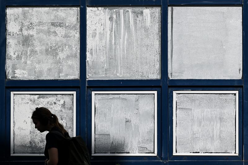 A woman walks front of a school with windows covered with Blanc de Meudon, a type of chalk powder, applyed by student's parents to protect the children from the heat during a heatwave in Nantes, western France. Photo: Sebastien Salom-Gomis/AFP via Getty Images