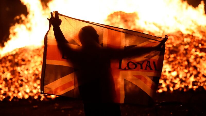 A man holds a Union flag in front of a bonfire in the Sandy Row area. Photograph: Reuters
