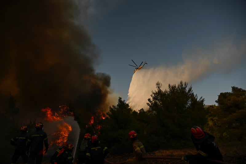A helicopter drops water over a smoke-filled forest during a wildfire near Porto Germeno, northwest of Athens, Greece. Photograph: Michael Varaklas/AP