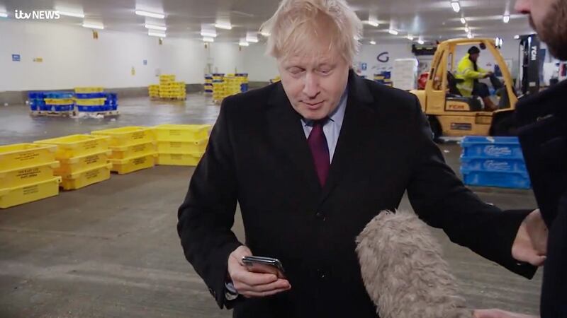 Screengrab from ITV of British prime minister Boris Johnson looking at a photograph of a four-year-old boy with suspected pneumonia having to sleep on the floor in a hospital because of a shortage of beds, on the phone of ITV reporter Joe Pike, after initially having removed the phone from Mr Pike and putting it in his pocket. Photograph: ITV/PA Wire