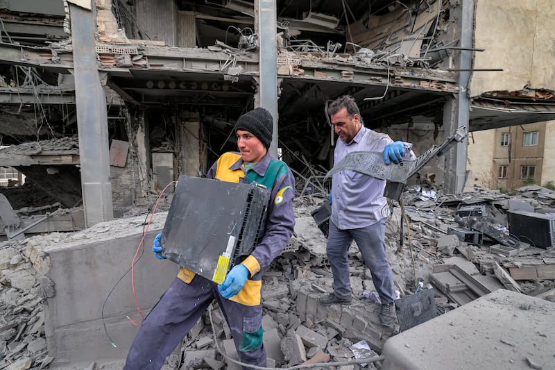People retrieve computer servers and equipment from an office building that housed the offices of the Doha-headquartered news network Al Araby TV following a missile strike earlier in the day in Tehran on Sunday. Photograph: Atta Kenare/AFP via Getty Images