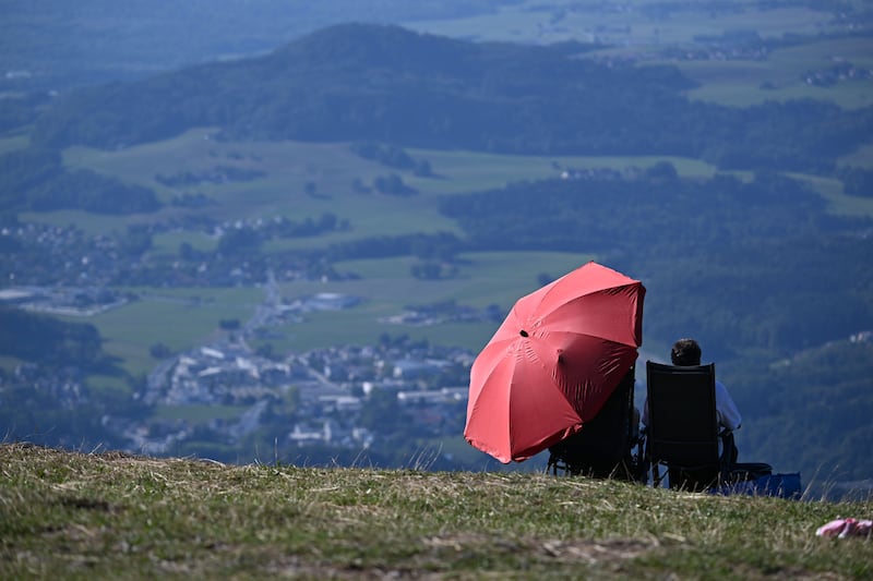 People shelter under an umbrella as they take their position to view the partial solar eclipse in Salzburg, Austria, on August 12th. Photo by Barbara Gindl/APA/AFP via Getty Images
