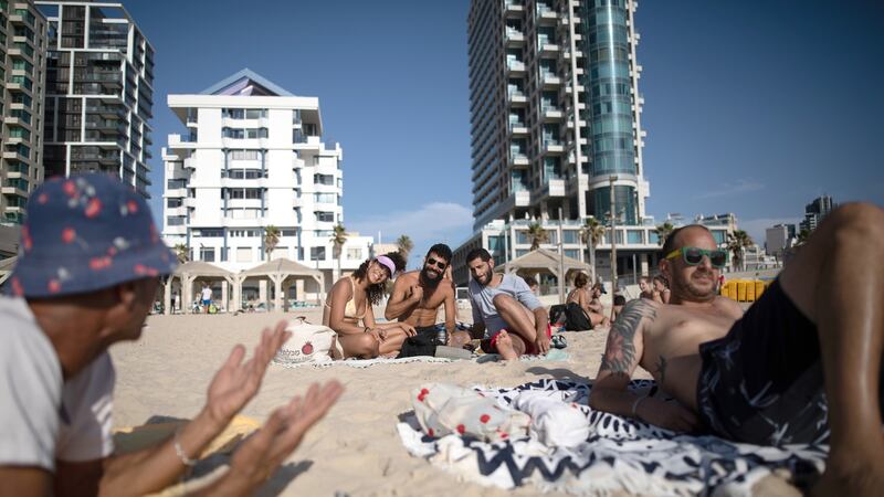 From left: Ben Levy, Sagi Assaraf and Neta Vashdi relax at the beach in Tel Aviv, Israel, on Sunday. Photograph:  Corinna Kern/The New York Times