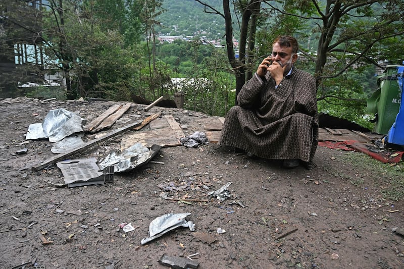 A local resident speaks on a mobile phone outside his house that was destroyed by Pakistani artillery shelling at the Lagama village in Uri, about 100km from Srinagar, India, in May. Photograph: Tauseef Mustafa/AFP via Getty Images        