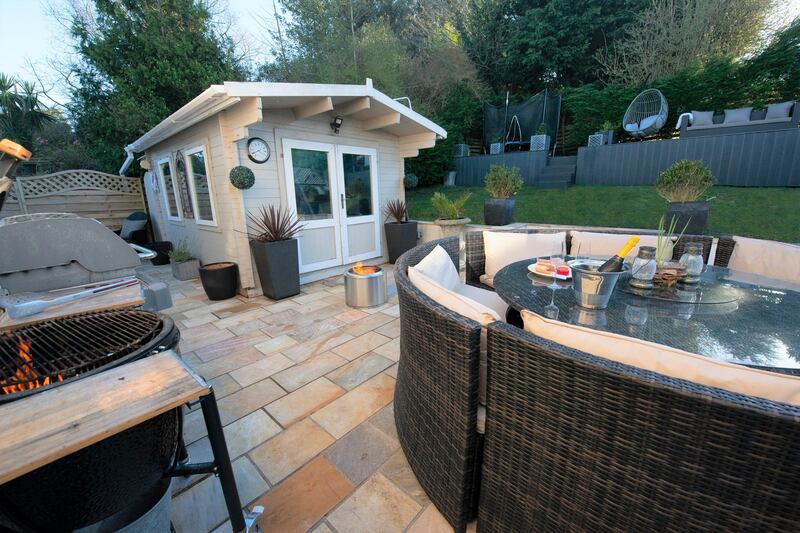 The rear garden, which includes a patio area and timber cabin