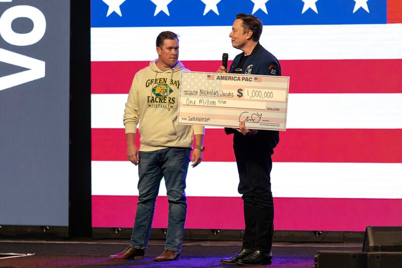 Elon Musk presents a cheque for $1 million to sweepstakes winner Nicholas Jacobs at a rally in support of Brad Schimel's candidacy for the Wisconsin supreme court. Photograph: Jim Vondruska/New York Times
                      