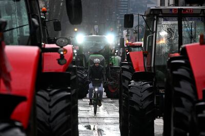 A man rides a bicycle past farmers' tractors during a protest in Brussels. Photograph: John Thys/AFP via Getty Images