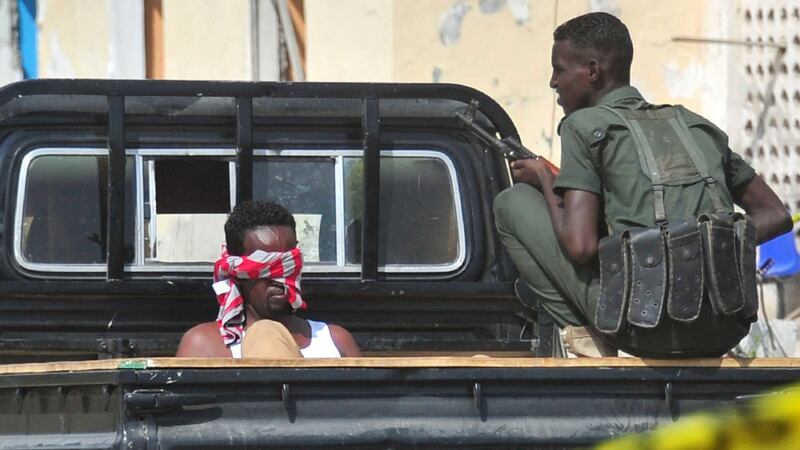 A Somali security officer(R) guards a suspected member of the al-Qaeda-linked Shabaab group detained at the scene of car bomb attack near the Mogadishu port on Sunday. Photograph: Mohamed AbiWahab/Getty Images
