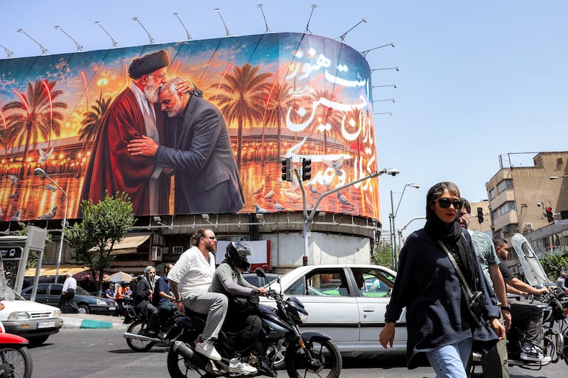 People cross a street past a billboard depicting Iran's slain supreme leader Ali Khamenei kissing the slain Islamic revolutionary guards commander Qasem Soleimani. Photograph: AFP via Getty Images