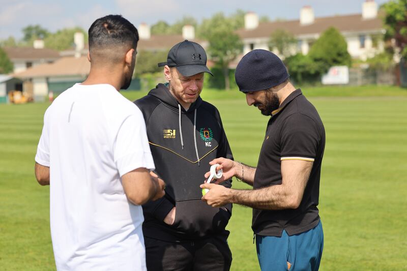 Kenny Carroll, from Railway Union Cricket Club, getting a lesson in taping a tennis ball from Kamran Kochai and Adnan Khan, as the club invited homeless asylum seekers to play cricket in Sandymount, Dublin. Photograph: Dara Mac Dónaill

