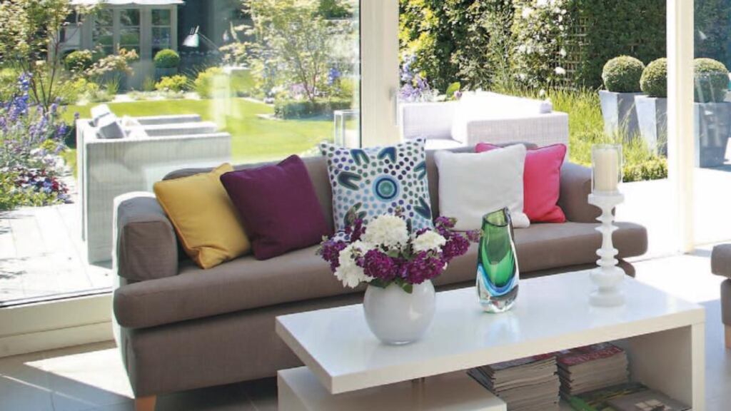 A mix of plain and coloured cushions pick up the colours of the flowers outside to connect the living space with the garden