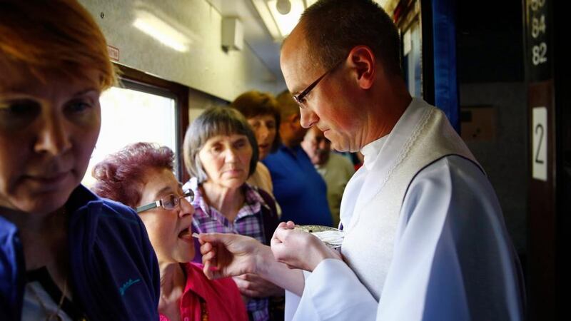 A priest distributes  Holy Communion to pilgrims on a train headed  towards Rome to witness the canonisations of Pope John XXIII and Pope John Paul II at the Vatican. Photograph: Kacper Pempel/Reuters.