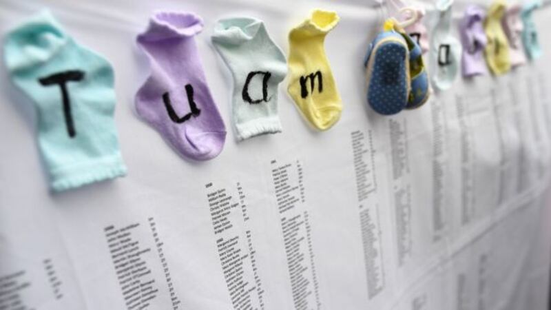 Baby socks and shoes are attached to the list of children names at the site of  where the remains of 796 babies where uncovered at a site of a former mother and baby home in Tuam, Co Galway. Photograph: Dylan Martinez/Reuters.