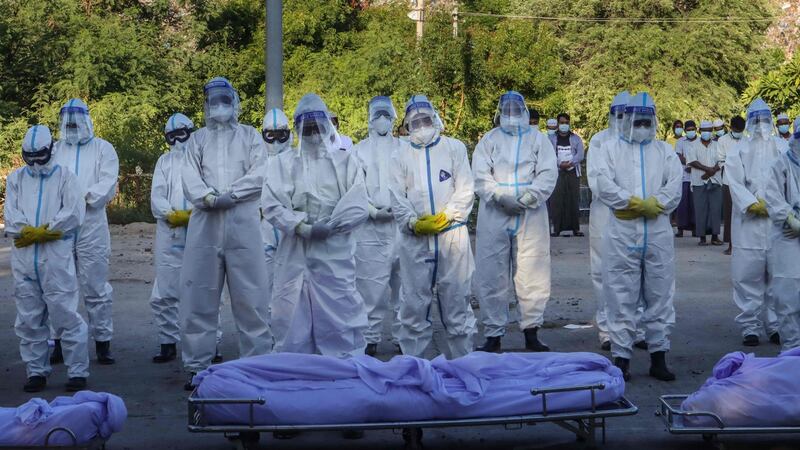 Volunteers wearing personal protective equipment  pray in front of bodies of people who died from Covid-19 during their funeral at a cemetery in Mandalay. Photograph:  AFP via Getty Images