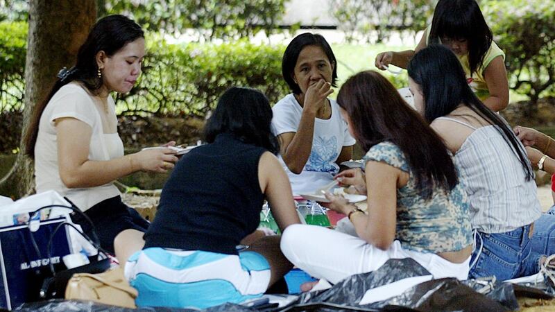 Domestic helpers enjoy a picnic in the shade at ‘Gulung-gulung’ park in Singapore, in 2003.  Photograph:   Roslan Rahman/AFP/Getty Images