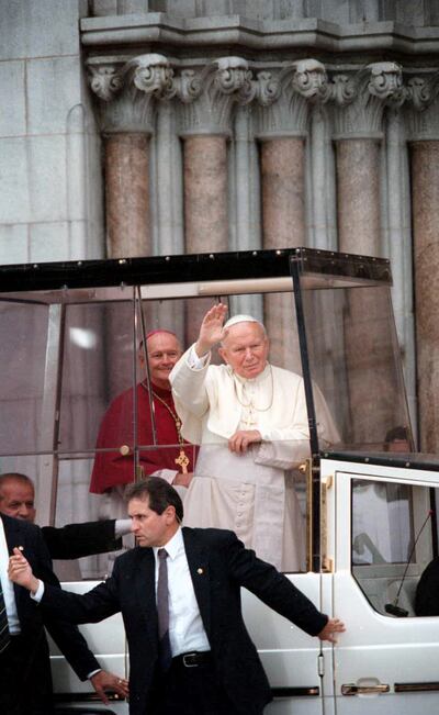 Pope John Paul II waves to the crowd as he arrives at the Newark Cathedral in Newark, New Jersey, in October 1995 as then-Cardinal Theodore McCarrick looks on from the background.  Photograph: Ozier Muhammad/The New York Times
                      