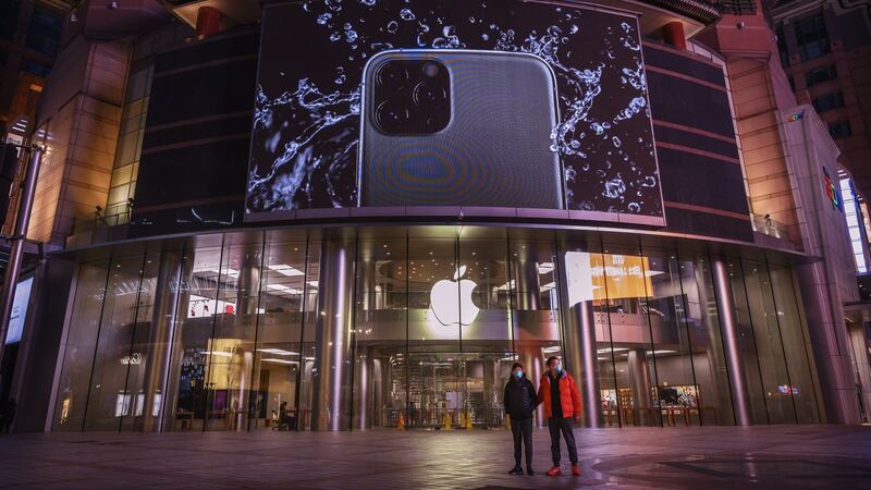 A couple wear protective masks in front of an Apple Store in a nearly deserted street in Beijing. Photograph: Kevin Frayer/Getty
