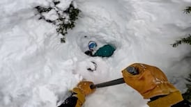 Moment skier happens upon snowboarder buried head-first under snow and digs him out