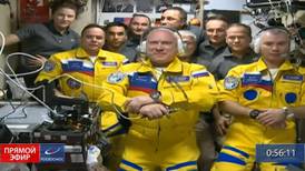 Russian cosmonauts board space station wearing yellow and blue flight suits